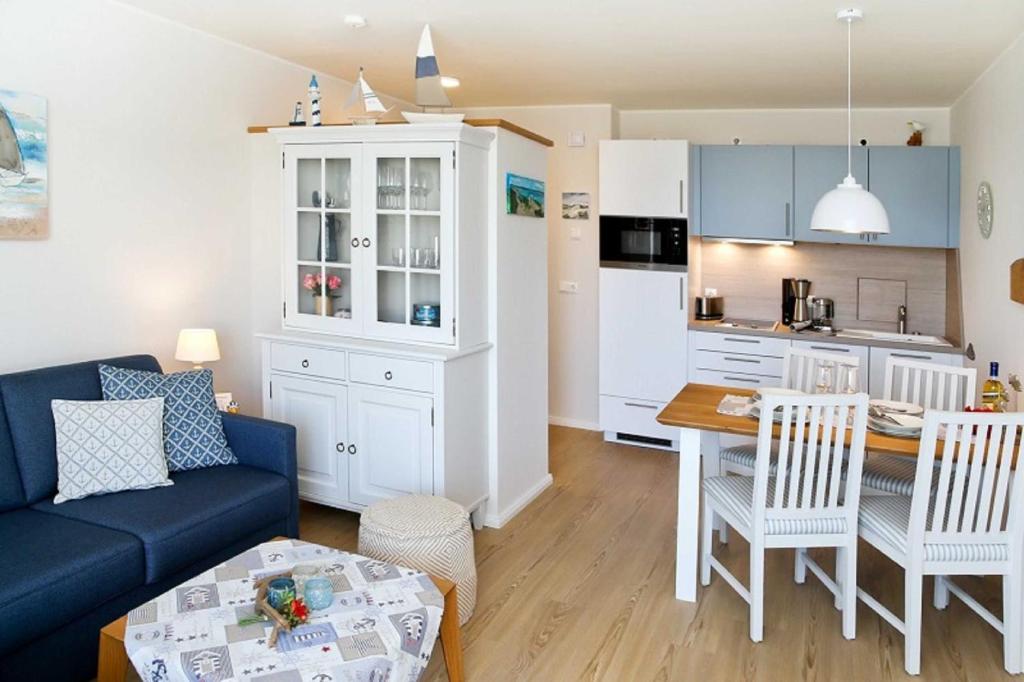 a living room with a blue couch and a kitchen at Fewo Rosenhof TW Queen in Kühlungsborn