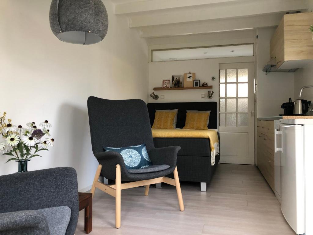 a bedroom with a bed and a chair and a couch at DeZwarteRuiter in Callantsoog
