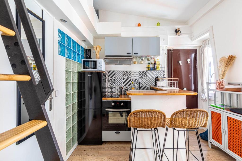 - une cuisine avec un réfrigérateur noir et deux tabourets de bar dans l'établissement GuestReady - Beau Séjour près de Canal St Martin, à Paris