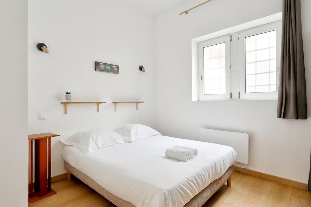 un lit blanc dans une chambre blanche avec une fenêtre dans l'établissement Modern 1BR Flat in the heart of Lille, à Lille