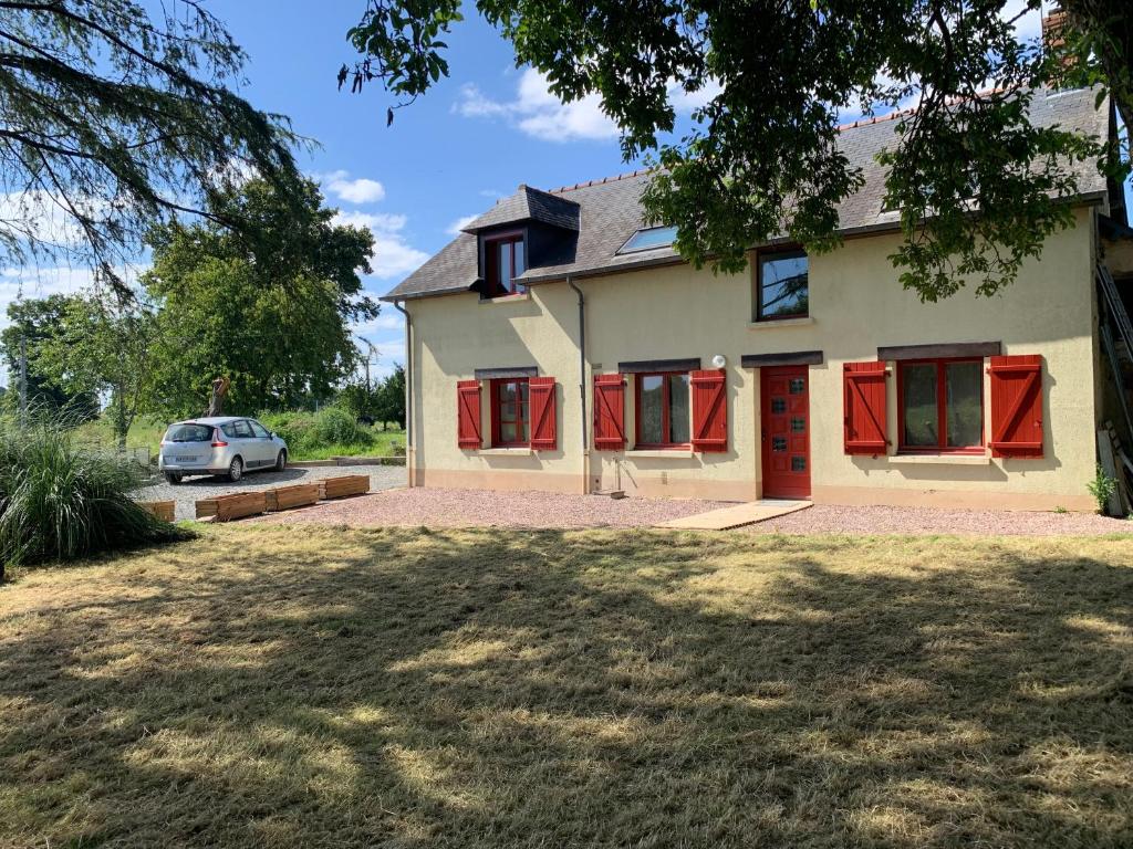 une maison avec des portes rouges et une voiture garée dans l'établissement Charmante maison aux portes de Rennes, à Mordelles