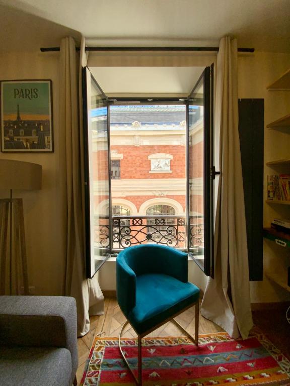 un salon avec une chaise bleue et une fenêtre dans l'établissement Buffon, à Paris