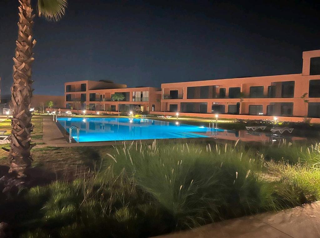 a building with a swimming pool at night at Appartement Noria Golf in El Makina