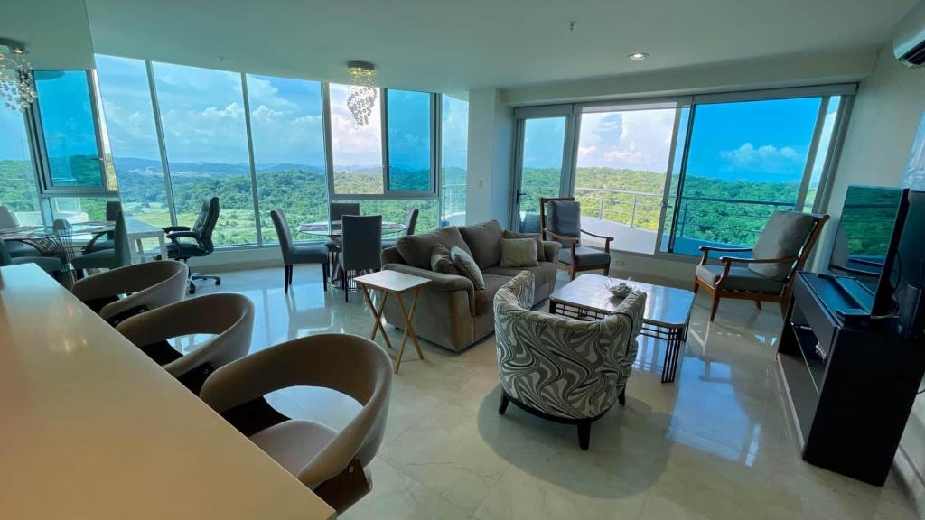 a living room with a couch and chairs and windows at Apartment with Spectacular Ocean Jungle Views in Playa Bonita Village