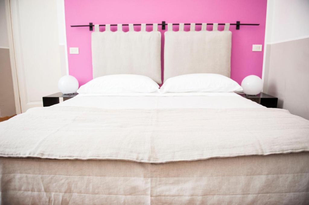 a bedroom with a large bed with a pink wall at Florian Rooms Guest House in Rome
