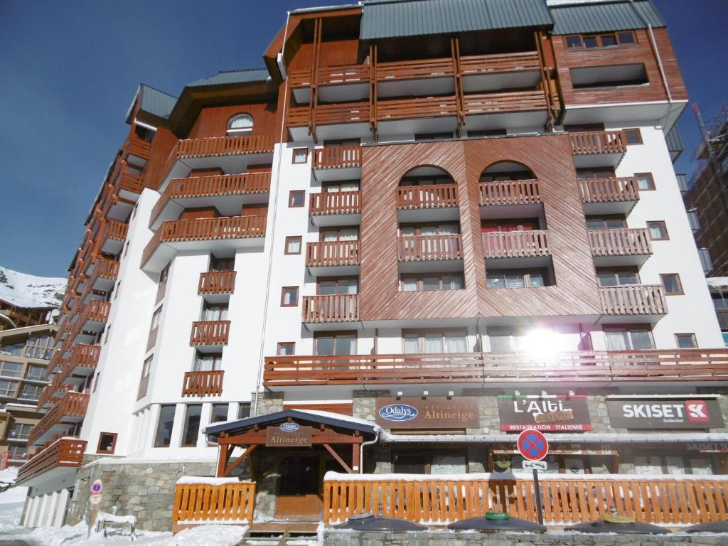 a tall white building with wooden balconies on it at Altineige in Val Thorens