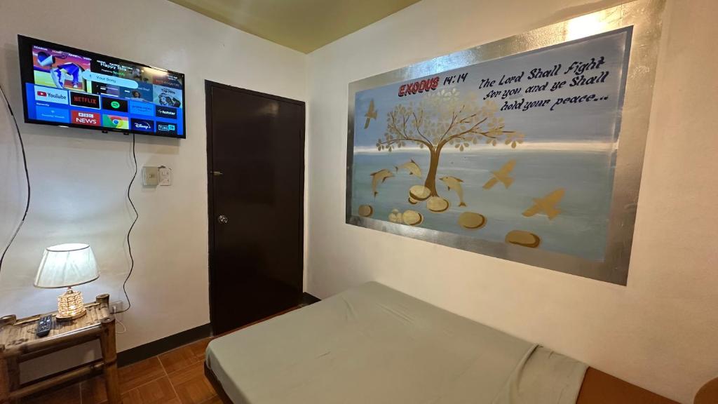 Zimmer mit einem Bett und einem Plakat an der Wand in der Unterkunft Orsan Apartelle in Pio Duran