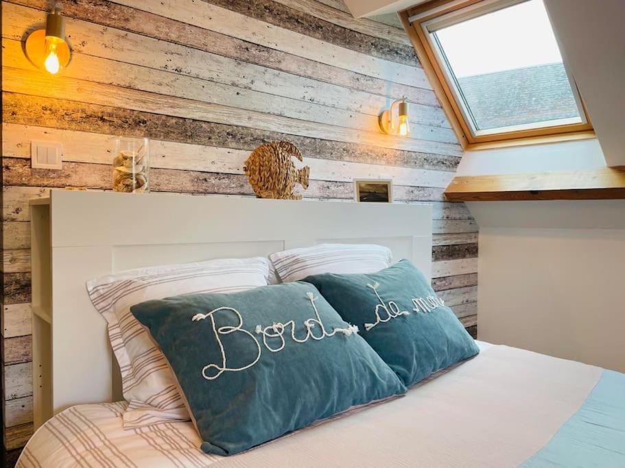 - une chambre avec un lit et un mur en bois dans l'établissement JolyHome, prestations de qualité entre Terre et Mer, à Maupertus-sur-Mer