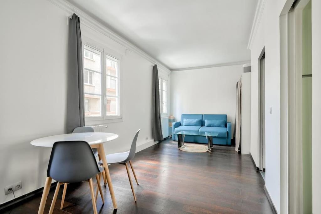un salon avec une table et un canapé bleu dans l'établissement Charmant studio - Paris Boulogne Marcel Sembat, à Boulogne-Billancourt