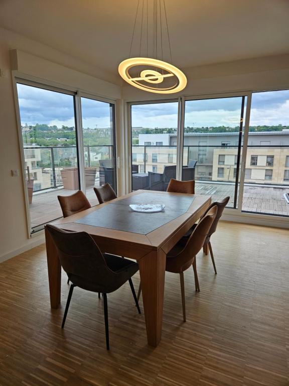 Una mesa de comedor con sillas y una gran ventana. en La Varenne Standing, en Chennevières-sur-Marne