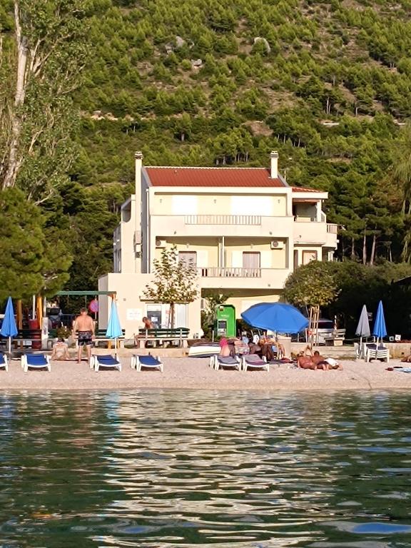 a building on a beach with chairs and umbrellas at Beach apartments Promajna in Promajna