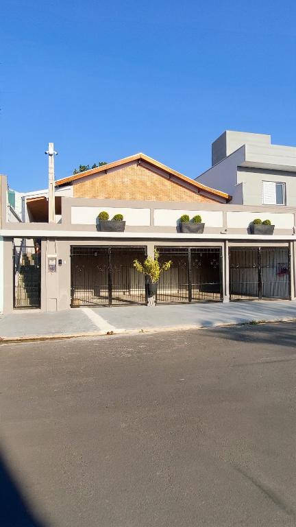 a white building with a fence and a street at HOSTEL ErreJota in Jaguariúna