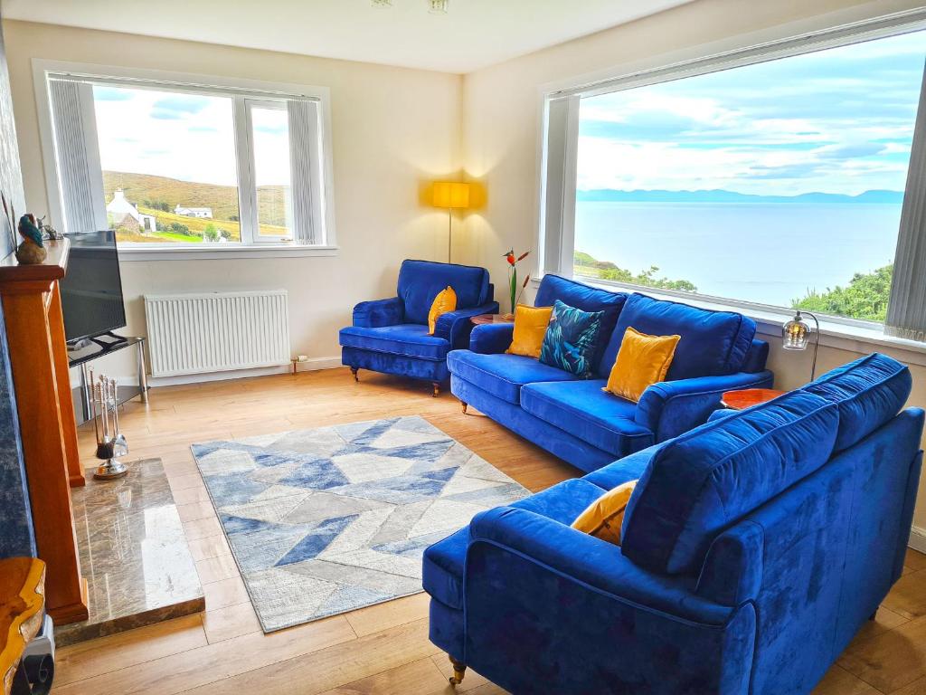 een woonkamer met twee blauwe banken en een groot raam bij Sunnyhill Cottage in North Erradale