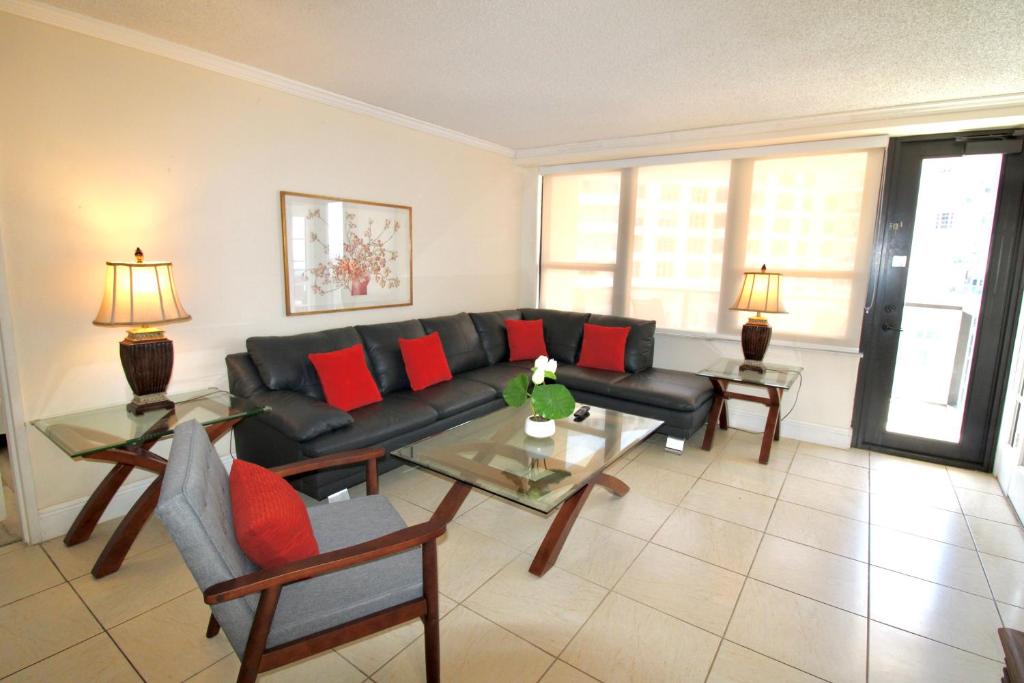 a living room with a black couch and red pillows at Alexander 1211 Beachfront Condo with Direct Beach Access, 2 Pools, Sauna, Gym in Miami Beach