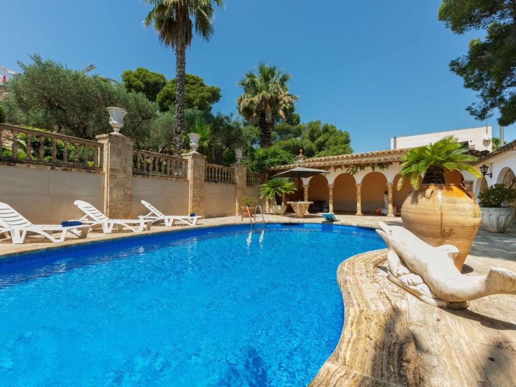 a swimming pool in a resort with chairs and palm trees at Villa Les Oliveres by Interhome in Llança