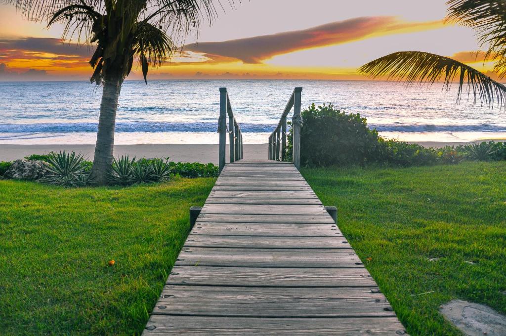 um caminho de madeira para a praia ao pôr do sol em Bahia Residence Cabarete em Cabarete