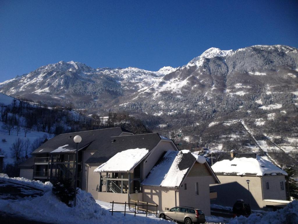 una casa ricoperta di neve con montagne sullo sfondo di Résidence Pyrénées Zenith a Luz-Saint-Sauveur