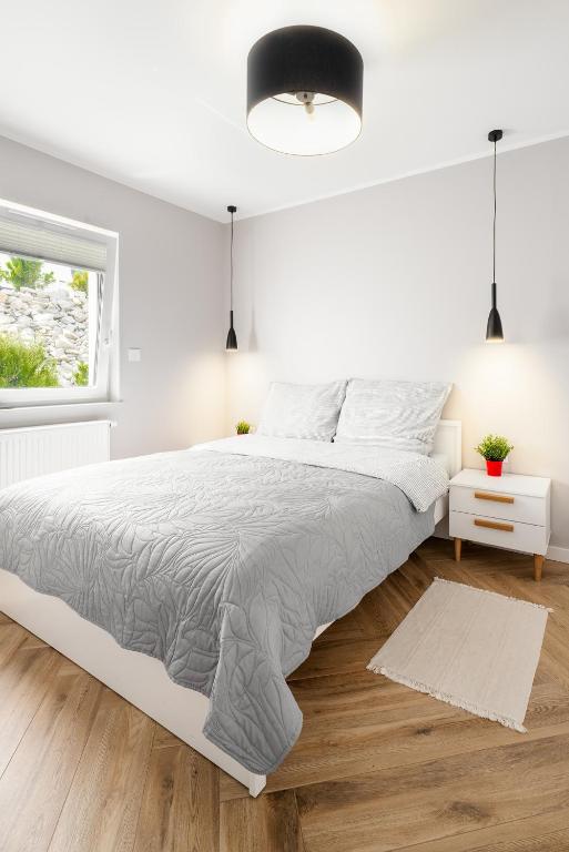 una camera da letto bianca con un letto grande e una finestra di Apartament Stacja Wisła a Wisła