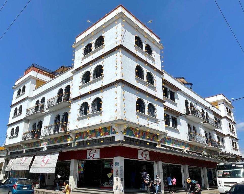 a tall white building with people standing in front of it at Hostal Andaina in Oaxaca City