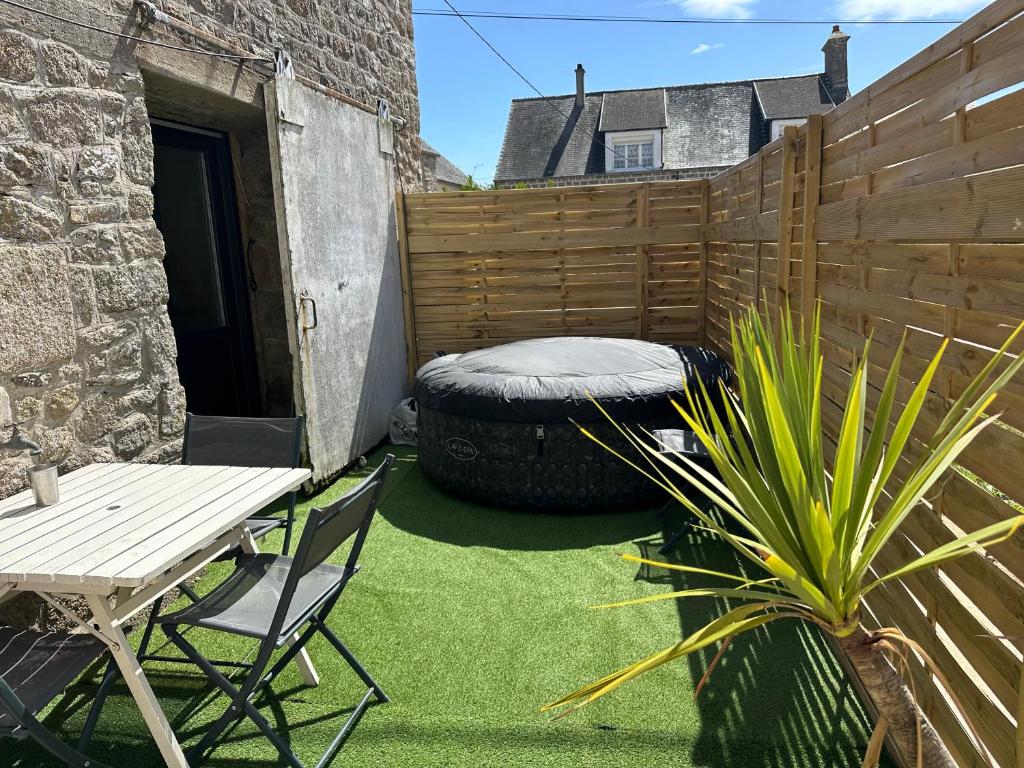 a patio with a table and a chair and a fence at Les jardins de Reville in Réville