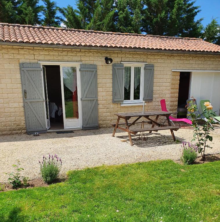 un hangar avec une table et un banc devant lui dans l'établissement La petite maison, à Aunac