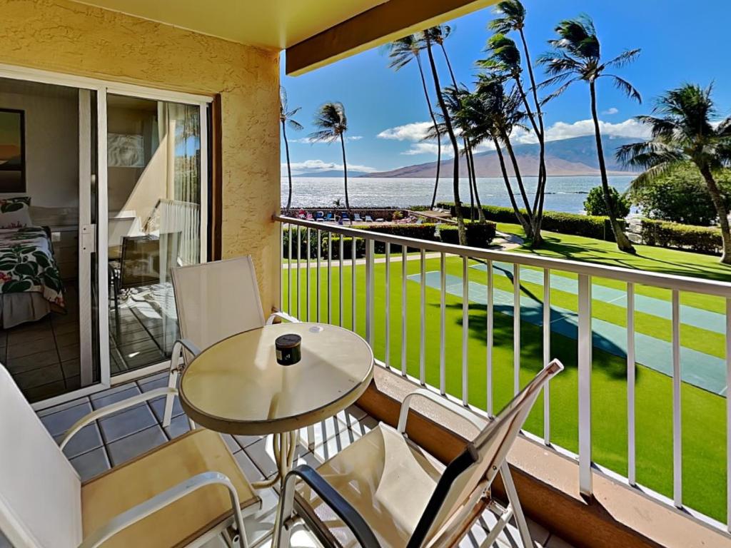 a balcony with a table and chairs and the ocean at Menehune Shores 206 in Kihei