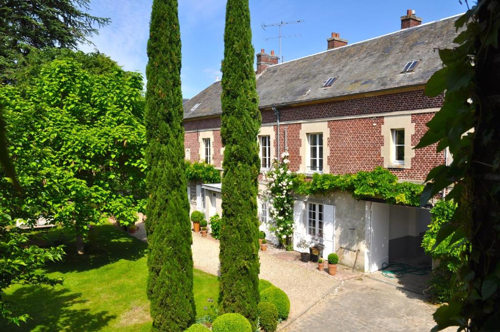 una casa con árboles delante de ella en La Maison & L'atelier en Neuilly-en-Thelle