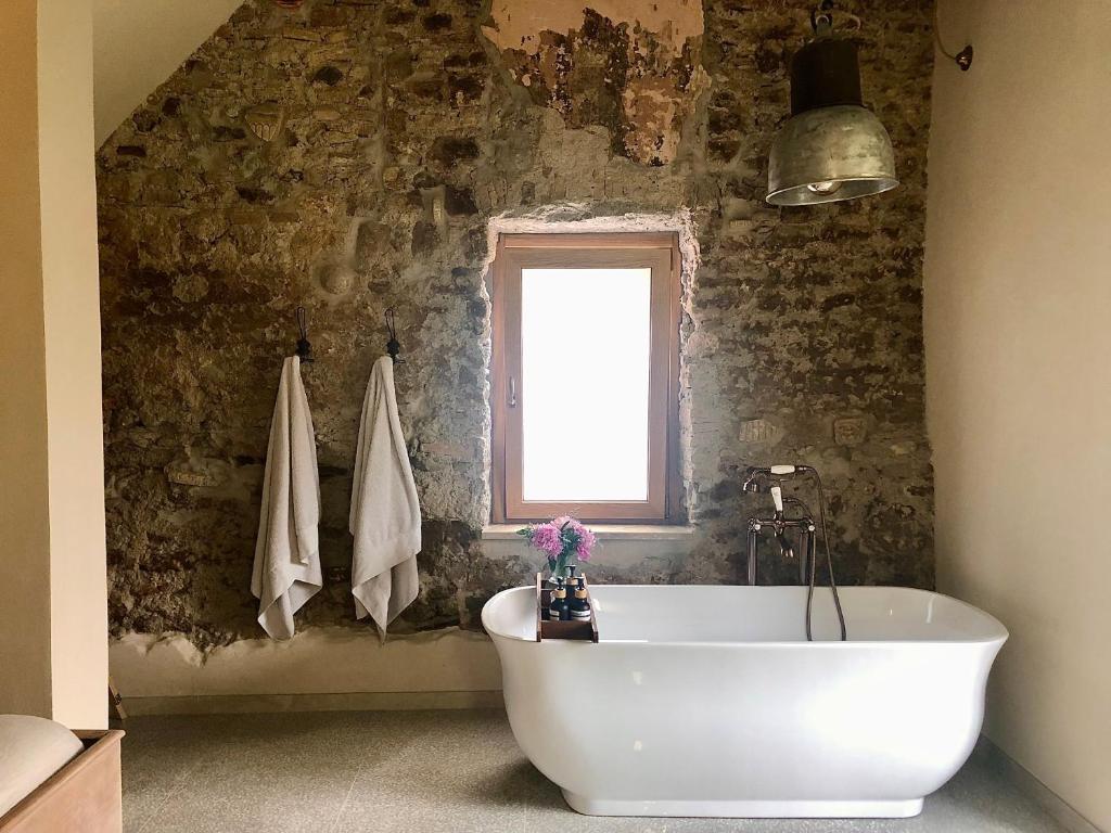 La salle de bains est pourvue d'une baignoire blanche et d'une fenêtre. dans l'établissement Amaretto, à Tivoli