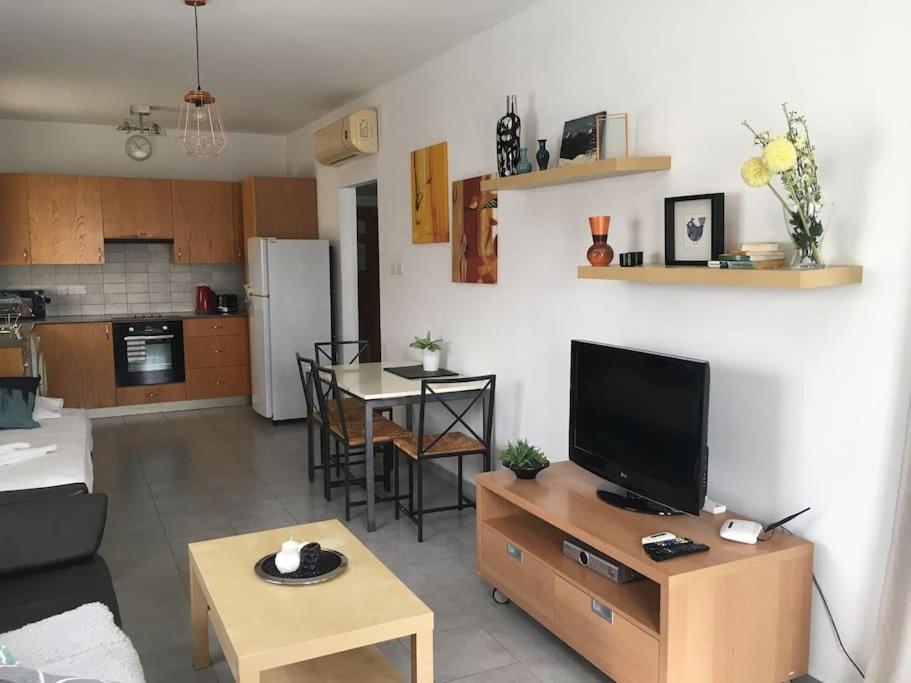 un soggiorno con TV e cucina di Olivia Budget Apartment a Paralimni