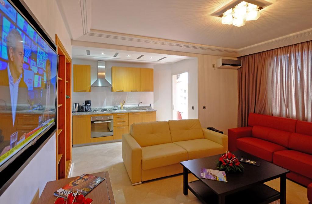 a living room with a red couch and a kitchen at Appart Hôtel Mouna in Marrakech