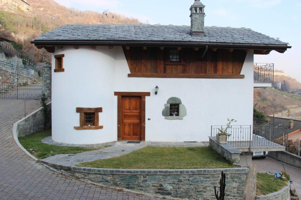 uma pequena casa branca com uma porta de madeira em Villa La Tour em Nus