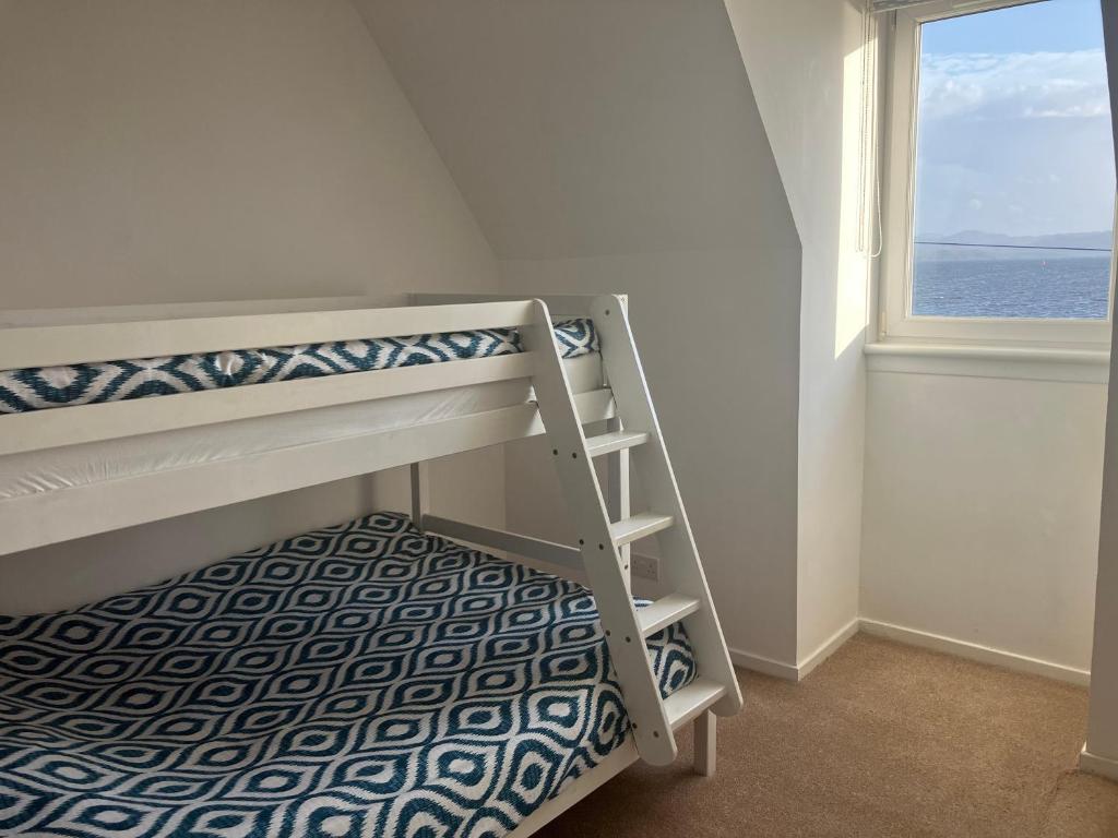 ein Schlafzimmer mit Etagenbett und Fenster in der Unterkunft Tigh Na Mara Holiday Home in Aultbea