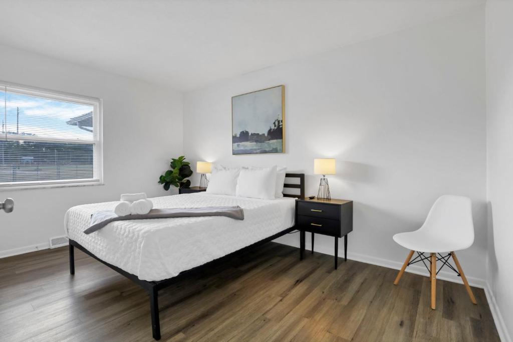 a white bedroom with a bed and a chair at The Northtowne Getaway in Columbus