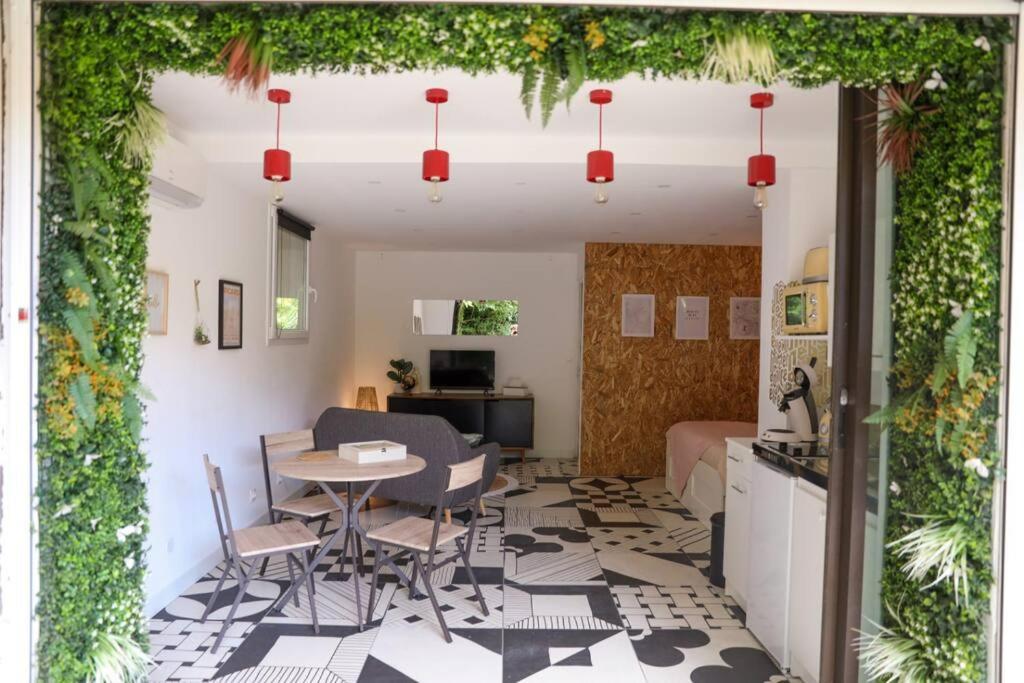 a living room with a table and chairs and a kitchen at Appartement rez-de-chaussée et patio in Romans-sur-Isère