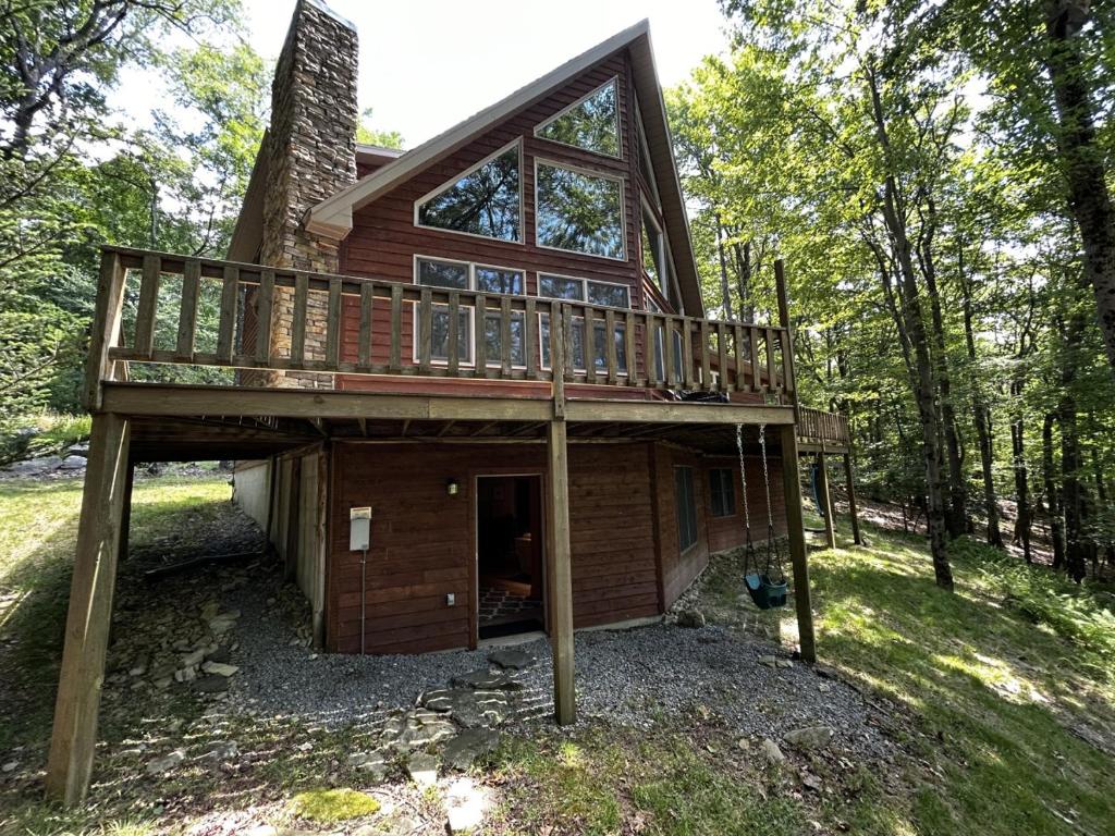 a house in the woods with a large deck at The Fox Den in Terra Alta