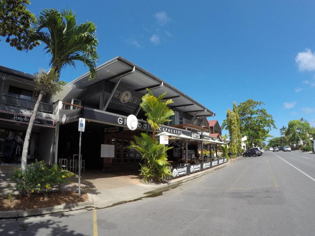 a building on the side of a street with palm trees at Global Backpackers Port Douglas in Port Douglas