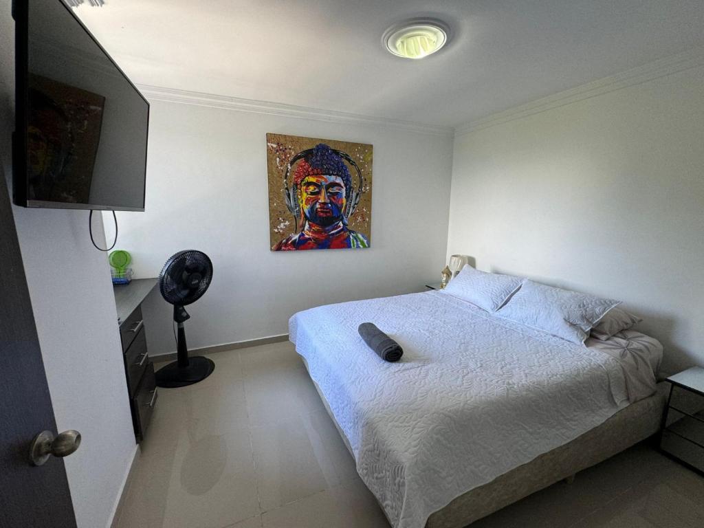 a bedroom with a bed with a painting on the wall at Espectacular Apartamento Ibagué in Ibagué