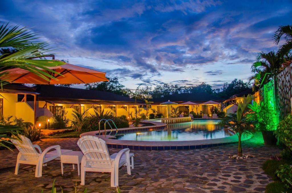 a resort pool with chairs and umbrellas at night at Panglao Homes Resort & Villas in Panglao Island