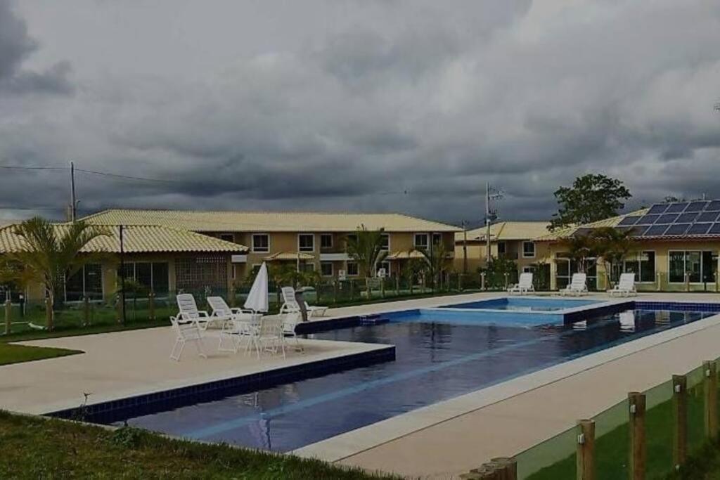 a swimming pool with white chairs and a building at APT Completo - Ar-condicionado, Wi-FI, piscina, garagem, portaria - aconchegante in Caruaru
