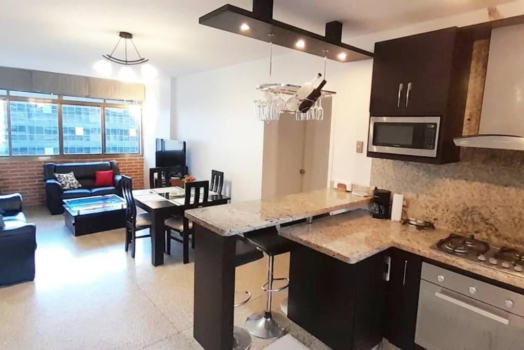 eine Küche und ein Wohnzimmer mit einem Tisch und einer Couch in der Unterkunft Moderno y Bonito Apto en Sebucan, Caracas in Caracas