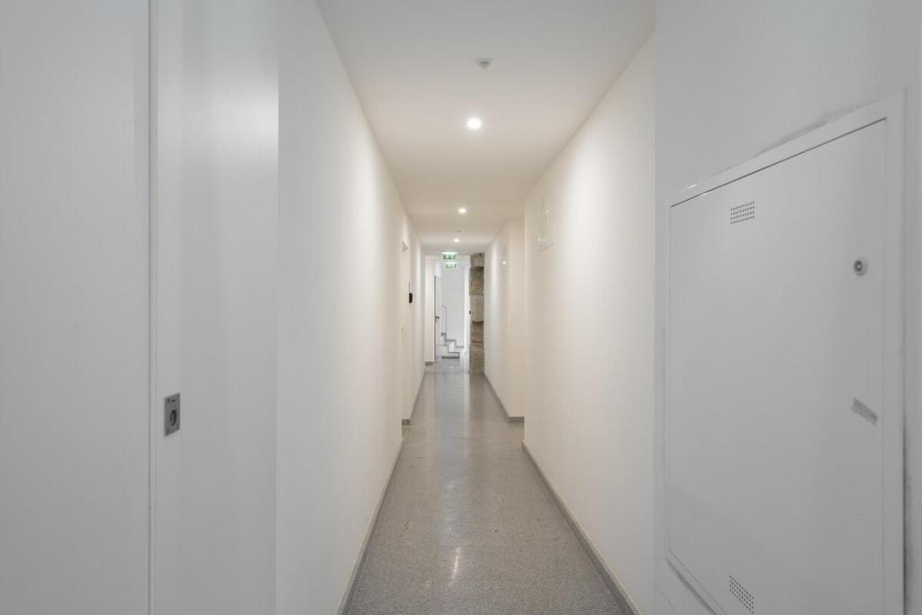 a hallway with white walls and a long corridor at Habitatio - Foz by LuxiStay in Porto