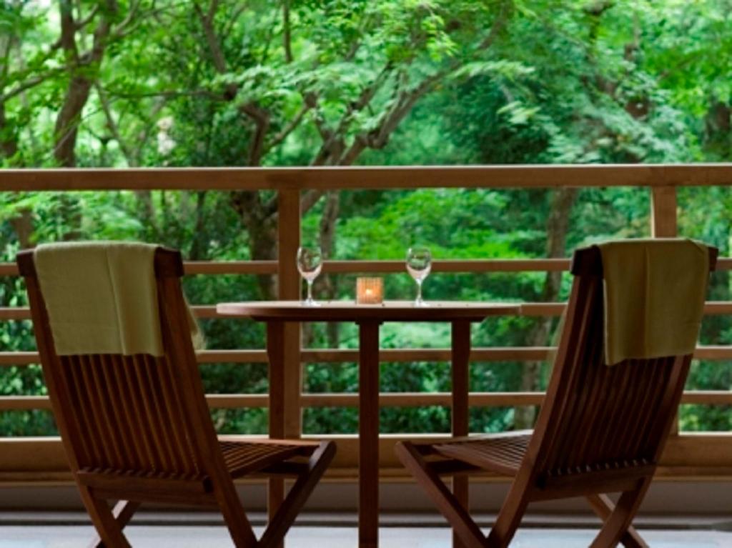 2 sillas y una mesa en un porche con copas de vino en Mizunoto, en Hakone