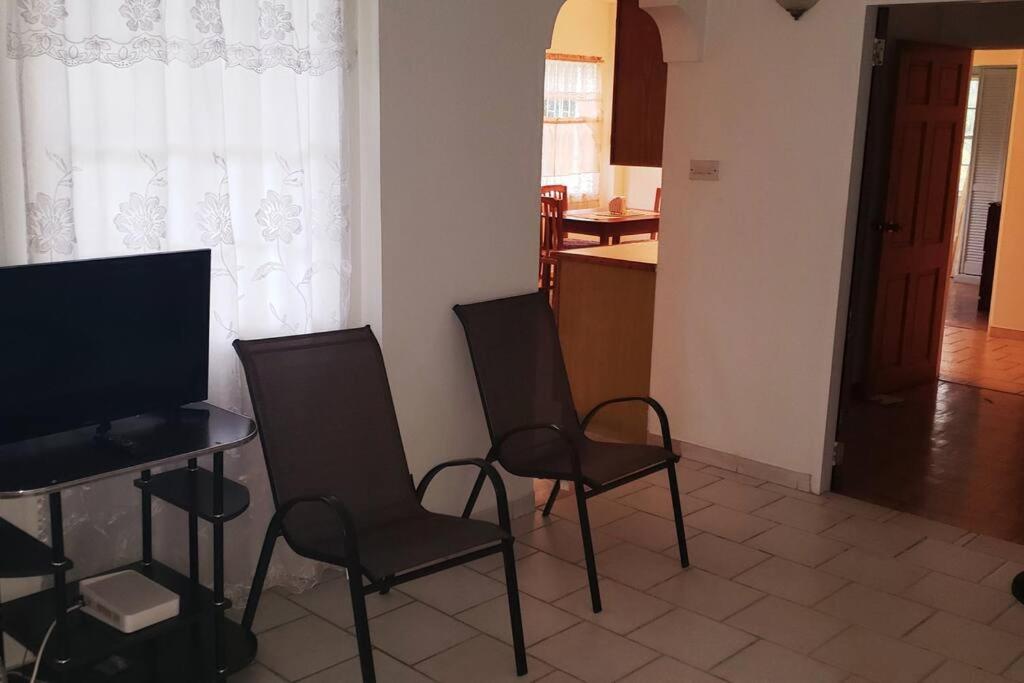 a living room with two chairs and a table with a television at Dominic Apt at Mt Hartman in Golflands