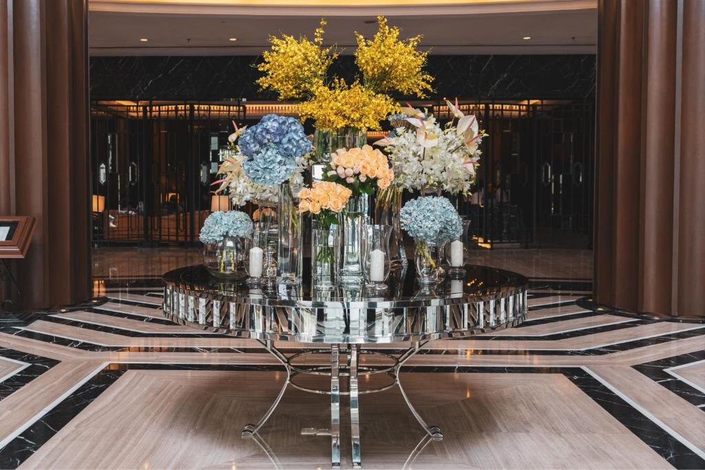 A large floral arrangement displayed on a mirrored table in a formal lobby.