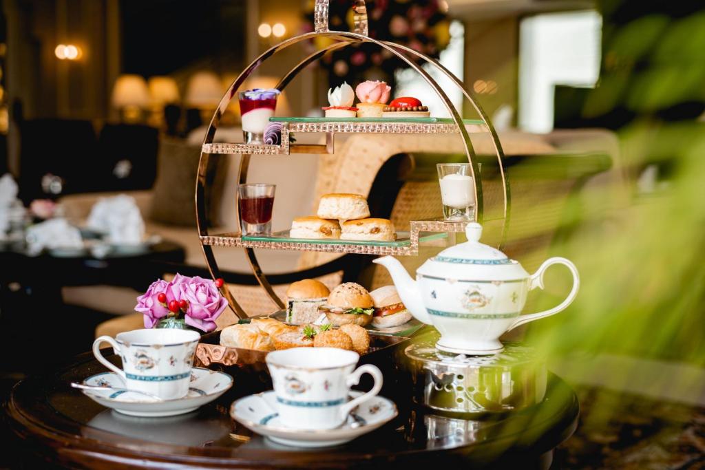 An afternoon-tea display of pastries, sandwiches and porcelain teaware.
