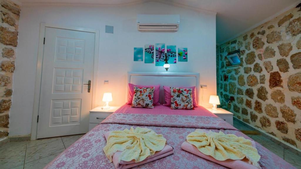 a bedroom with a bed with pink sheets and pillows at Villa atılgan in Kaş