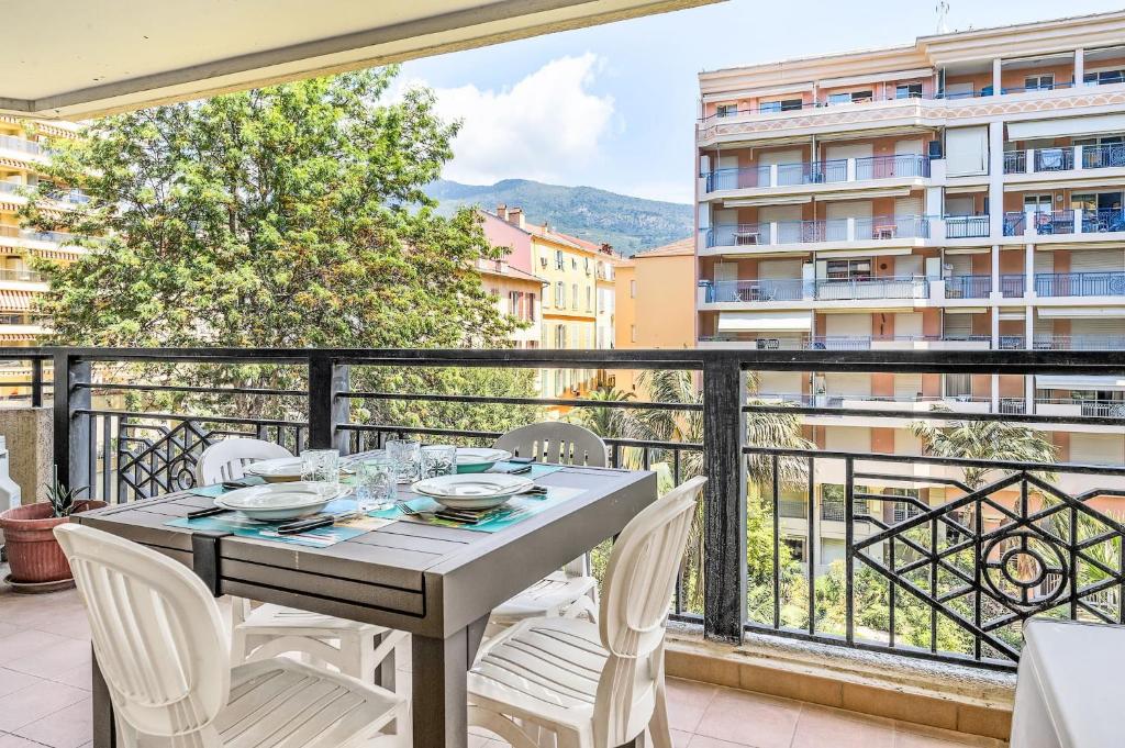 une table et des chaises sur un balcon avec vue sur un immeuble dans l'établissement Splendide 2 pièces Vue Jardin, Calme, Plein Centre, à Menton