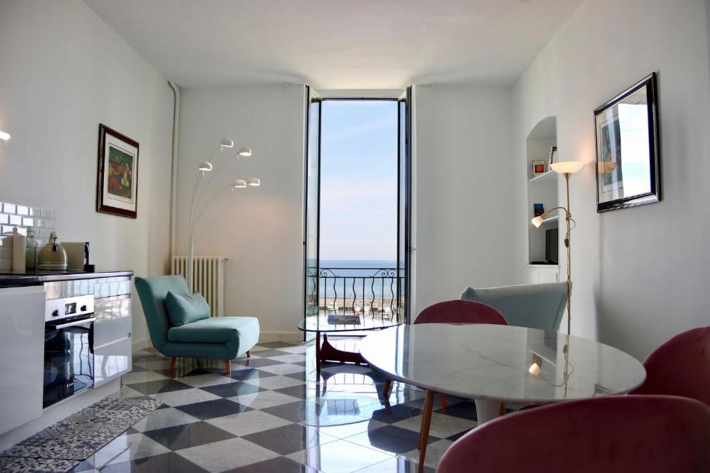 una sala de estar con una mesa y sillas de cristal en "Le Grand Hotel" Prestigieux et Unique, Vue Mer, en Menton