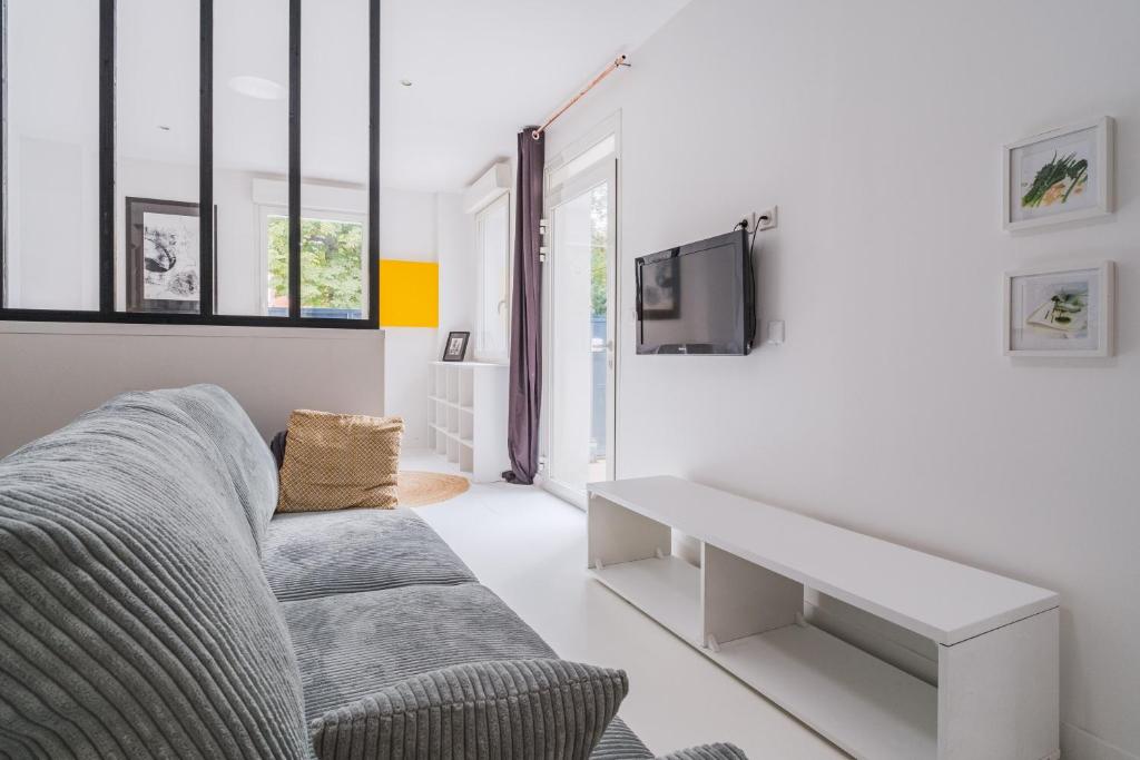 un salon avec un canapé et une télévision dans l'établissement Le Minautore - Charmant studio climatisé, à Toulouse