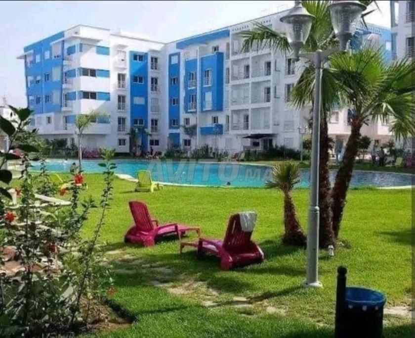 dos sillas rojas sentadas en el césped frente a un edificio en Amira luxury home, en Martil